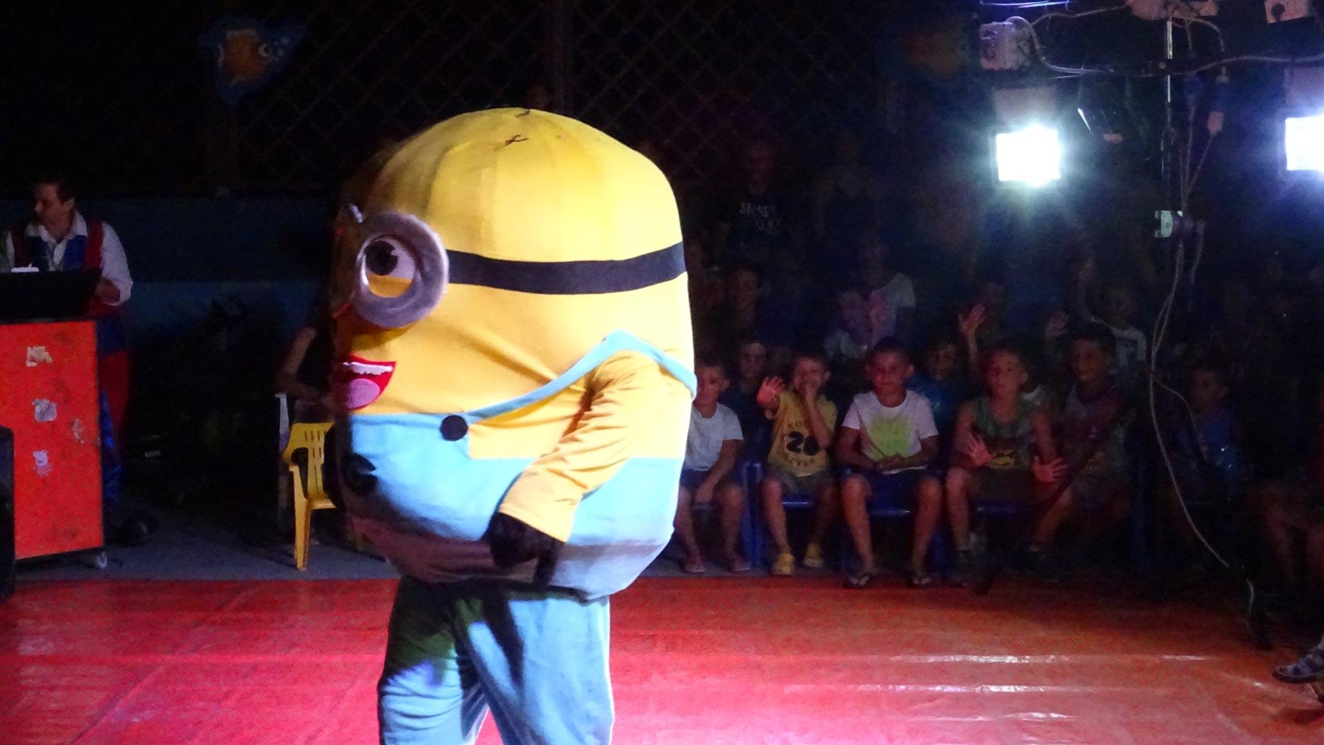 Person im Minion-Kostüm tritt vor Kindern bei einer Veranstaltung auf.