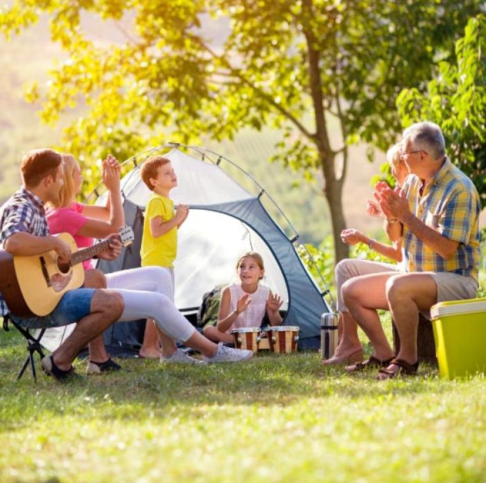 Happy family camping, playing musical instruments, and enjoying the outdoors.