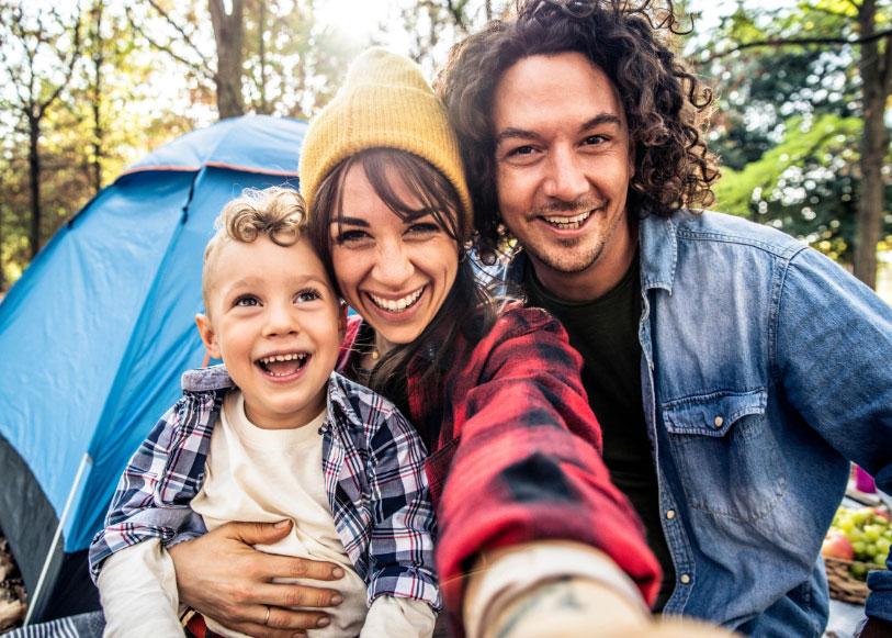 Famiglia felice in campeggio con tenda, sorridenti e all'aperto.