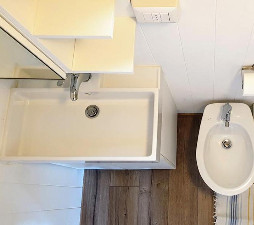 Bathroom with sink, bidet, and toilet, wooden floor.