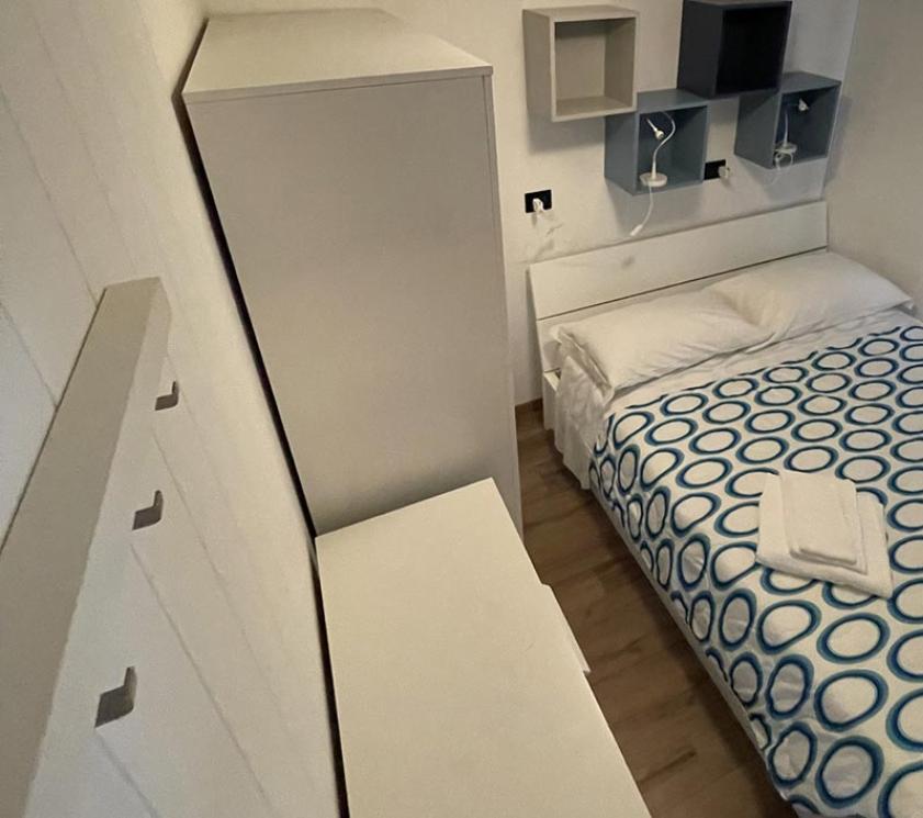 Camera da letto minimalista con letto matrimoniale e mobili bianchi.