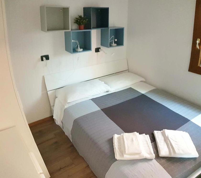 Camera da letto moderna con letto matrimoniale, scaffali e asciugamani piegati sul letto.