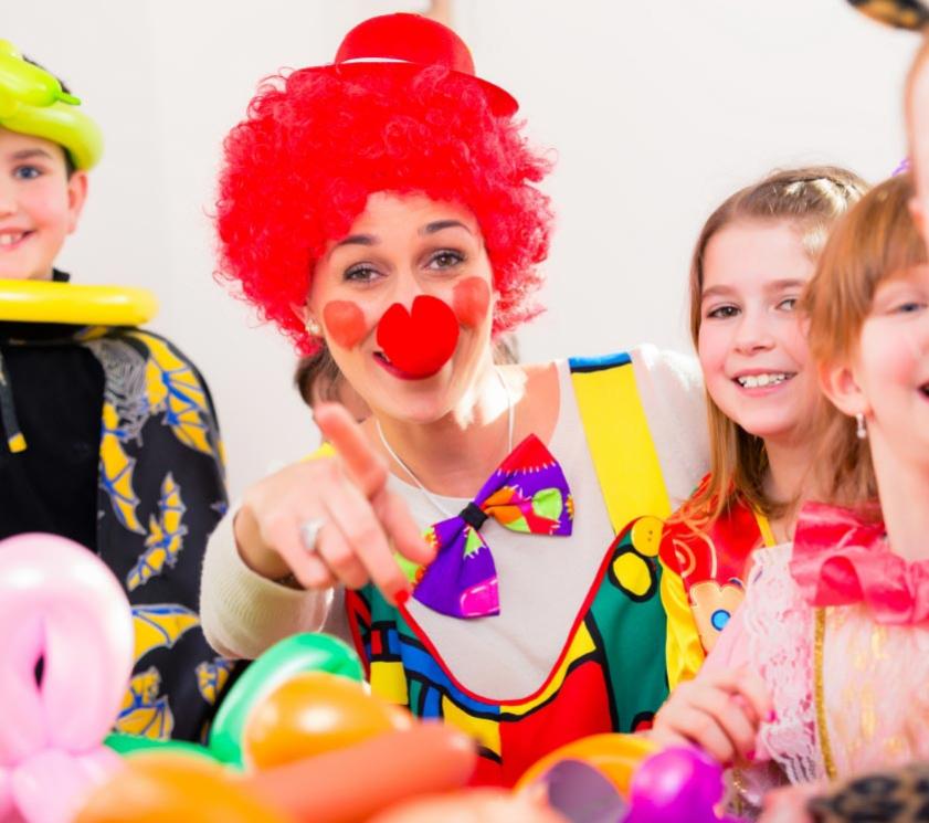 Clown con bambini felici durante una festa con palloncini colorati.