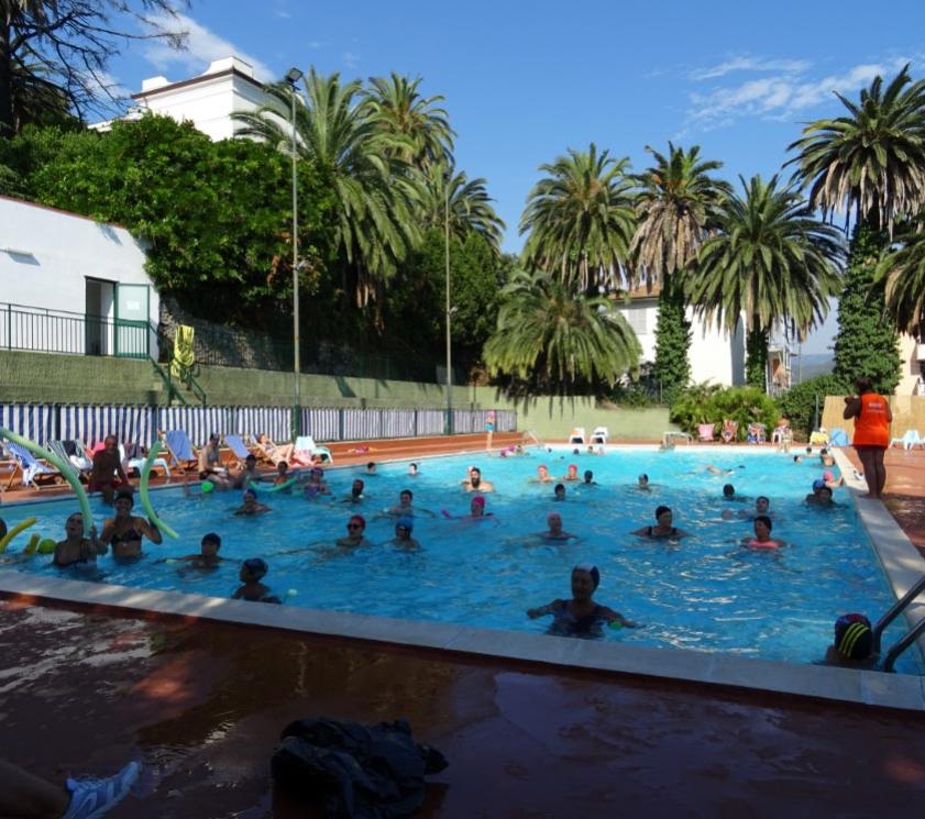 Outdoor pool with people swimming and relaxing.