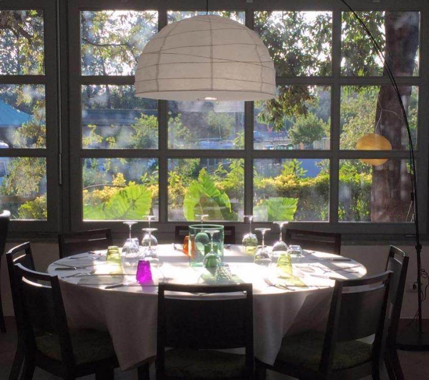 Set table in a bright restaurant with a garden view.