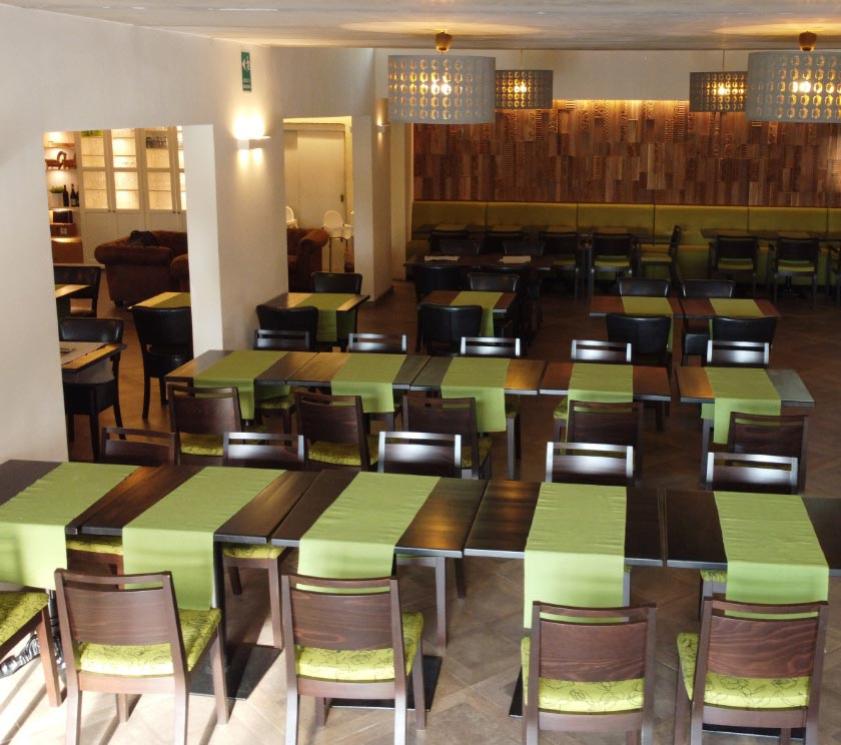 Restaurant chaleureux avec tables dressées et chaises vertes.