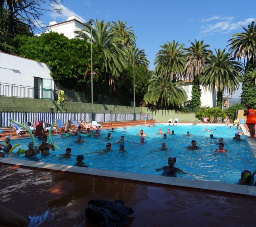 Des personnes dans une piscine participent à une activité aquatique sous le soleil.